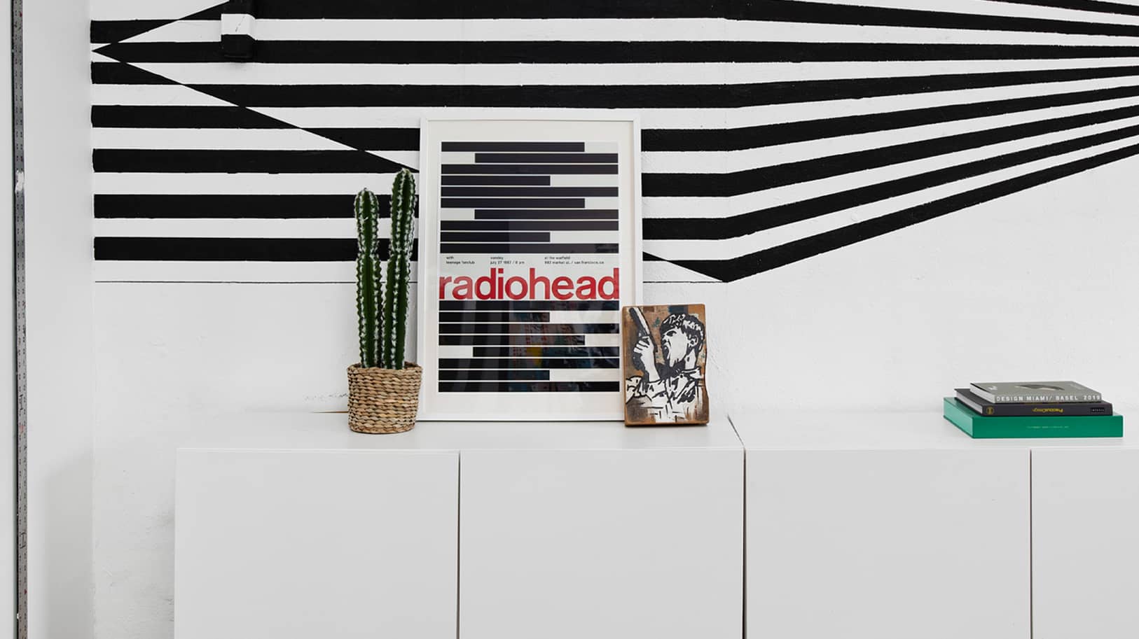 Cactus, Radiohead poster and books on top of white cabinet | Think Twice studio